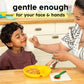 Woman feeding a child spaghetti with a napkin in a kitchen setting, with text 'gentle enough for your face & hands'
